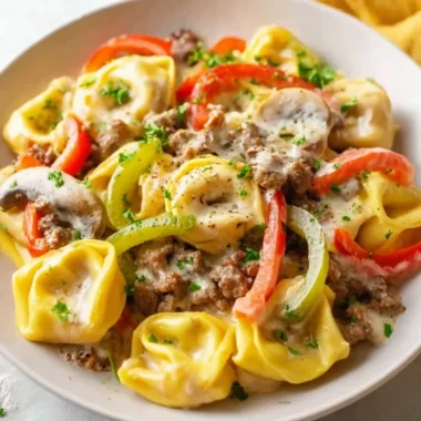 A bowl of Crock Pot cheesesteak tortellini topped with cheese and herbs.