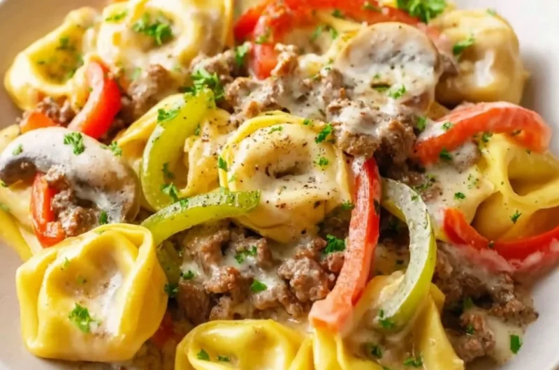 A bowl of Crock Pot cheesesteak tortellini topped with cheese and herbs.
