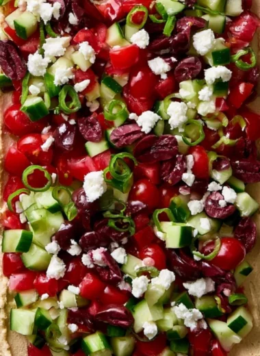 Delicious layered Greek dip topped with fresh vegetables and feta cheese