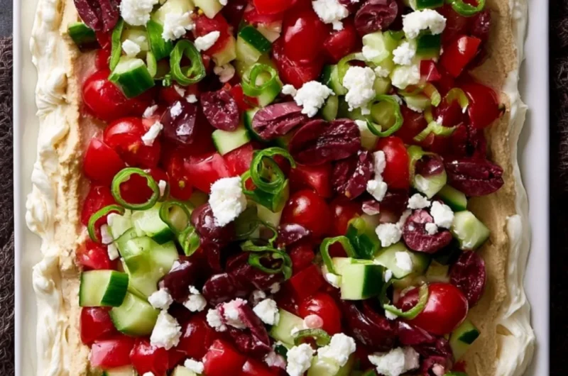 Delicious layered Greek dip topped with fresh vegetables and feta cheese