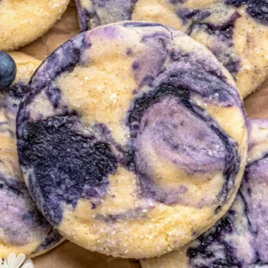 Lemon blueberry cheesecake cookies on a plate with fresh blueberries