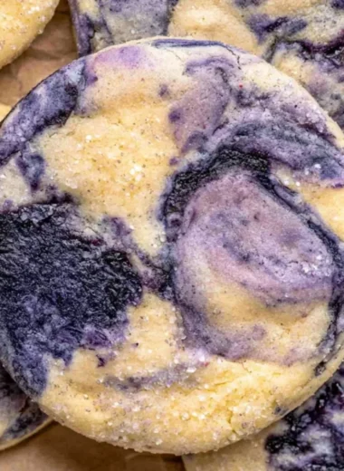 Lemon blueberry cheesecake cookies on a plate with fresh blueberries