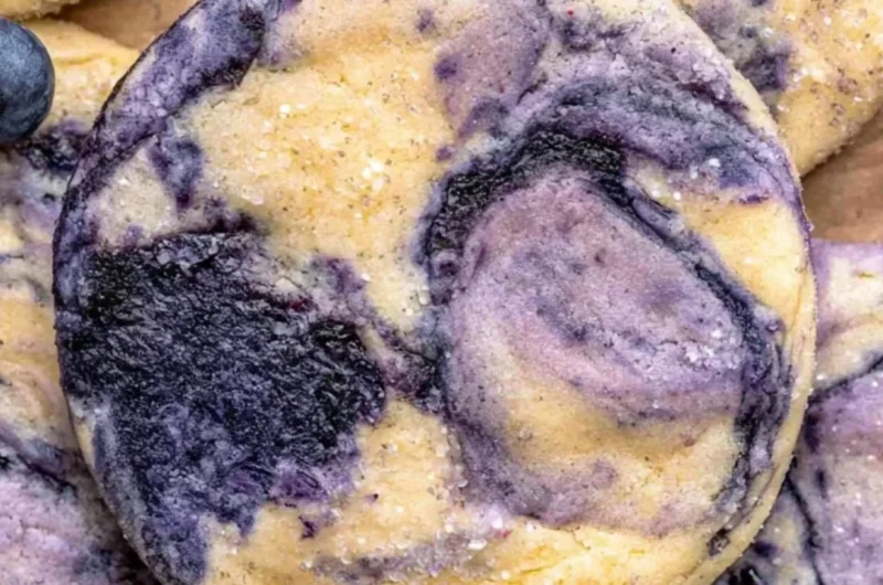 Lemon blueberry cheesecake cookies on a plate with fresh blueberries
