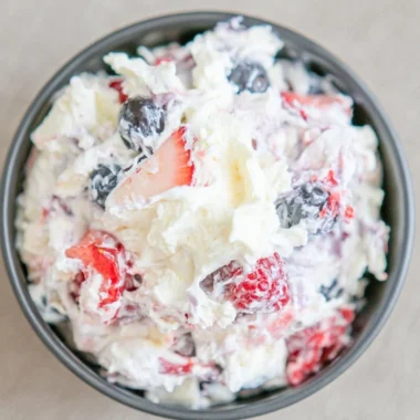 Delicious ultimate cheesecake salad topped with fresh fruits and whipped cream