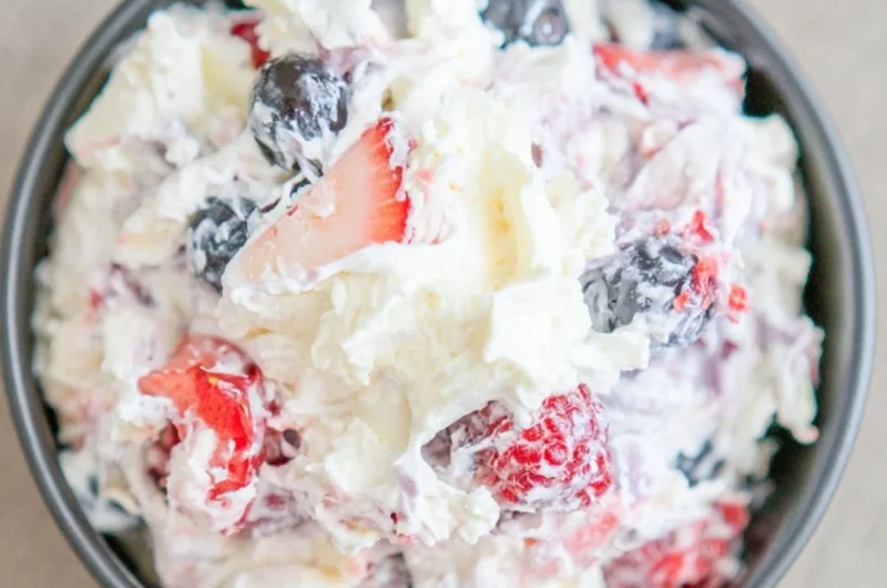 Delicious ultimate cheesecake salad topped with fresh fruits and whipped cream