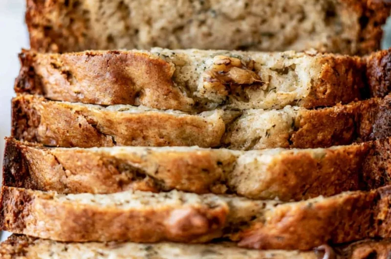 Deliciously baked easy banana bread loaf sliced on a wooden table.