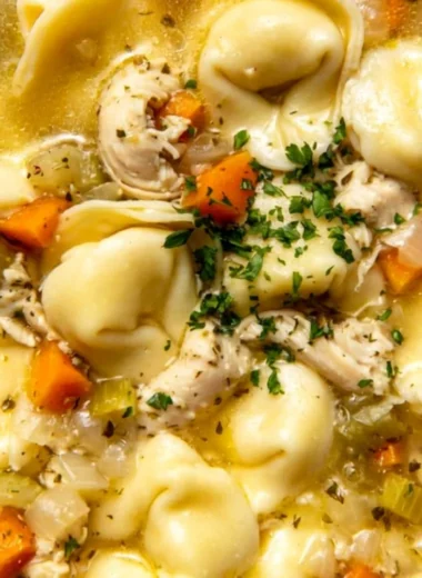 A bowl of delicious Chicken Tortellini soup garnished with herbs and vegetables.