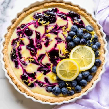 Creamy lemon tart drizzled with blueberry sauce, an irresistible dessert treat.