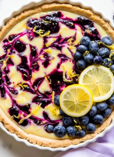 Creamy lemon tart drizzled with blueberry sauce, an irresistible dessert treat.