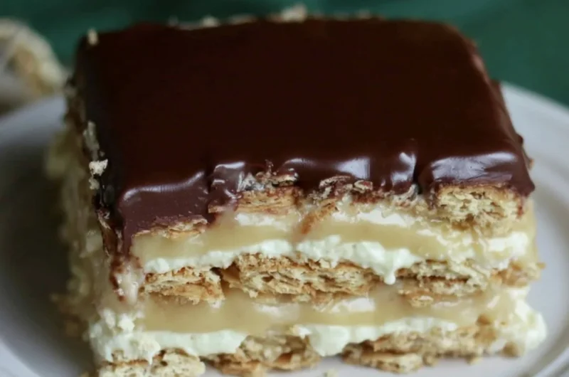 Delicious Eclair Icebox Cake layered with cream and chocolate on a serving plate