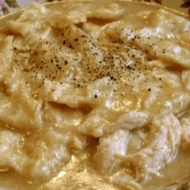 Bowl of homemade chicken and dumplings with vegetables and herbs
