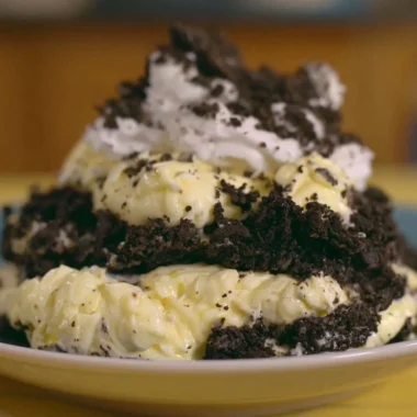 Delicious dirt pudding topped with crushed Oreos and gummy worms in a clear cup.