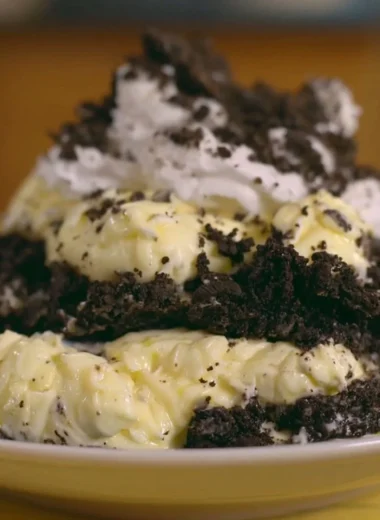 Delicious dirt pudding topped with crushed Oreos and gummy worms in a clear cup.
