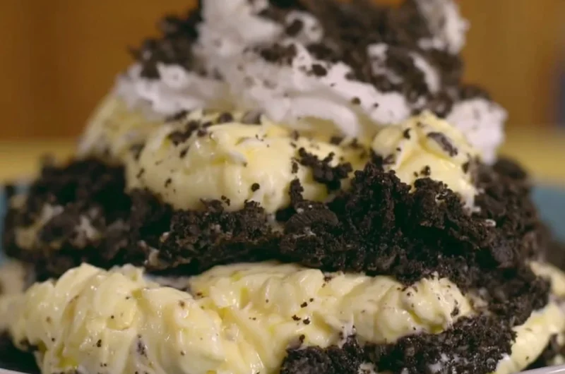 Delicious dirt pudding topped with crushed Oreos and gummy worms in a clear cup.