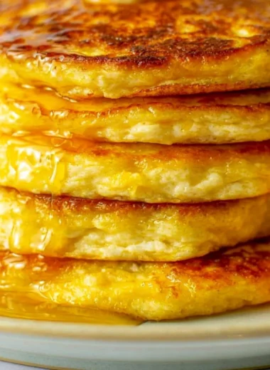Plate of fluffy orange ricotta pancakes topped with syrup and orange zest