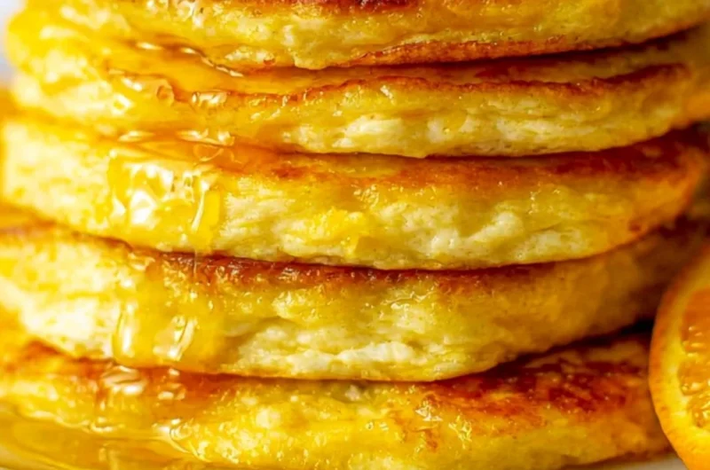 Plate of fluffy orange ricotta pancakes topped with syrup and orange zest