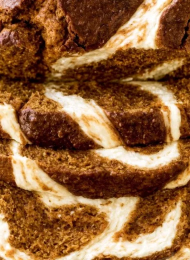 Pumpkin Cream Cheese Bread loaf with cream cheese swirls on a wooden table
