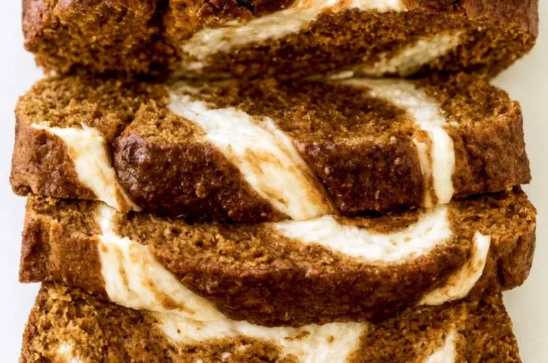 Pumpkin Cream Cheese Bread loaf with cream cheese swirls on a wooden table